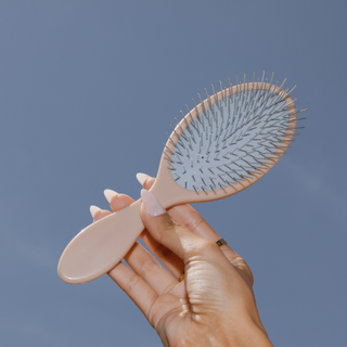 Model using Glow Beauty Detangling Brush on hair